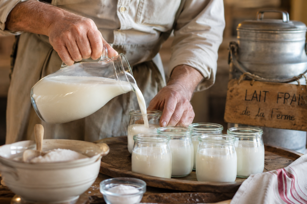 Thomas verse du lait frais dans des pots de yaourt artisanaux dans le laboratoire de la ferme Adelle en Bourgogne